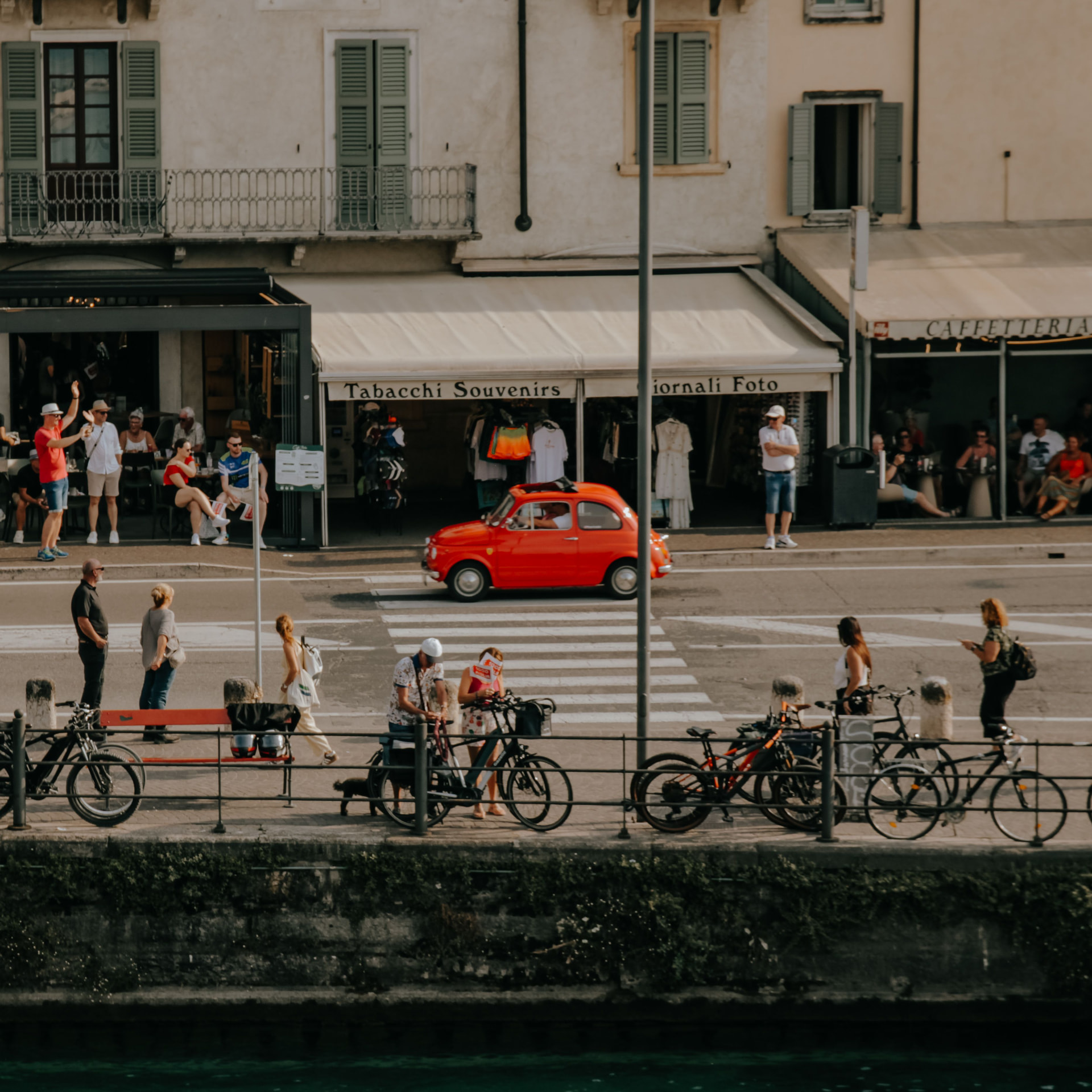 Italian lakeside street with a classic red car and cafés